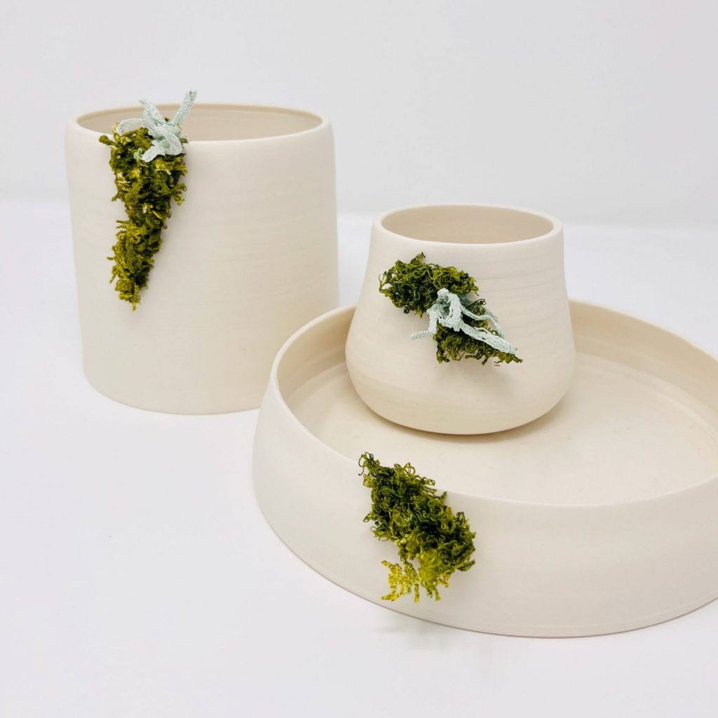 Three porcelain vessels with machine-embroidered moss and lichen.